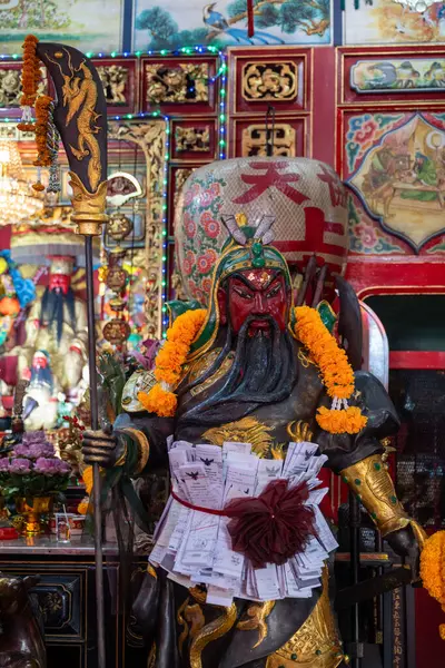 Tayland, 11 Ağustos 2024, Guan Yu Tapınağı (Khlong San), çiçeklerle süslenmiş geleneksel bir savaşçı tanrı heykeli, şenlikli bir kutlama sırasında canlı bir tapınakta duruyor.