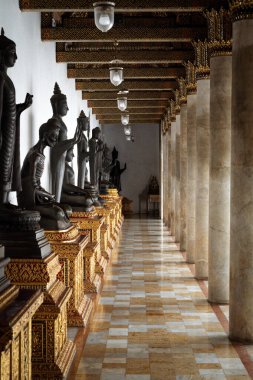 Tayland, 11 Ağustos 2024, Wat Benchamabophit Dusitwanaram, Şık koridor bir tapınakta gün ışığında karmaşık tasarım sergilenen heykellerle dolu.