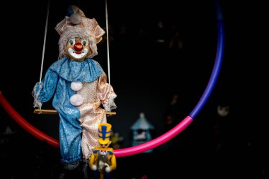 Canlı bir çemberde renkli kıyafetler giyen bir palyaço bebeği sallanıyor. Yakınlarda, büyüleyici oyuncaklar ve dekorasyonlar nostalji ve neşe uyandıran neşeli bir atmosfer yaratıyor..