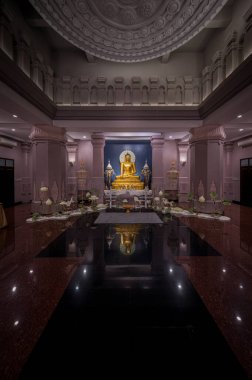 Ziyaretçiler, namaz kılmak ve altın Buda heykeline hayran olmak için Wat Panyanantaram 'ın huzur salonunda toplandılar. Sakin atmosfer, yumuşak ışık ve yansıtıcı yüzeylerle güçlenir..