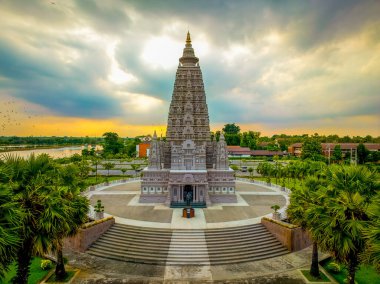 Wat Panyanantaram, Tayland 'ın Pathum Thani üzerinde güneş batarken çarpıcı bir mimari sergiliyor. Canlı bulutlar sıcak renkleri yansıtır, tapınağın huzurlu atmosferini güçlendirir..