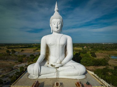 Tayland 'ın Ang Thong kentindeki Wat Muang' da huzur içinde duran görkemli beyaz Buda heykeli yapım aşamasında. Yeşillik ve tarlalar Nisan 'da güzel bir zemin oluşturur.