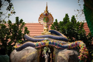 Ziyaretçiler, Şubat ayında Chonburi, Tayland 'daki Wat Hupbon Wanaram' da renkli süslemeler ve yemyeşil çiçeklerle süslenmiş büyüleyici altın Buda heykeline hayran kaldılar..