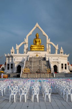 Lopburi, Tayland 'da, insanlar Puttha Sathan Lopburi Sri Suvarnabhumi' deki görkemli altın Buda heykelinin önünde, katılımcılar için hazırlanmış sandalyelerle dini bir etkinlik için bir araya geldiler..