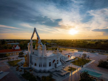 Puttha Sathan Lopburi 'nin üzerindeki gökyüzünü aydınlatan güzel günbatımı, yemyeşil manzaralar ve huzurlu bir atmosferle çevrili tapınağın zarif mimarisini gözler önüne seriyor..