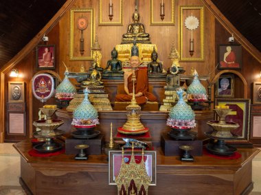 Ziyaretçiler, Wat Pa Thammawisut Mongkhon 'daki karmaşık dini eserlerle çevrili meditasyon yapan sakin bir keşişin Tayland ruhaniliğinin özünü yakaladığını gözlemliyor..