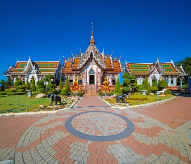 Nakhon Pathom 'daki Wat Srisathong' da Aralık ayında açık mavi bir gökyüzü altında manikürlü bahçelerle çevrili çarpıcı mimari ve ayrıntılı tasarımlar yer alıyor. Ziyaretçiler barışçıl atmosferin tadını çıkarıyor.
