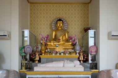 Wat Khiriwong, Nakhon Sawan, Tayland 'da çiçeklerle süslenmiş altın Buda heykeli Kasım ayının sakin bir gününde ziyaretçileri düşünmeye ve hayranlığa davet ediyor..