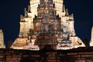 Phra Nakhon Si Ayutthaya 'daki Wat Chaiwatthanaram' ın ürkütücü gece manzarası ayrıntılı harabeleri ve karanlık gökyüzüne hafifçe aydınlatılmış Buda heykelleri..