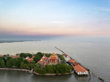 Ziyaretçiler, Tayland 'ın Samut Prakan kentindeki Wat Khun Samutrawat üzerinde nefes kesen günbatımına hayran kalırken, sakin sular ve canlı doğa huzurlu bir atmosfer yaratıyor..
