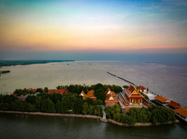 Wat Khun Samutrawat 'ın bu huzurlu görüntüsü, Samut Prakan' da Ocak ayı günbatımının canlı renklerini yansıtan, suyla çevrili tapınak kompleksini yakalar..