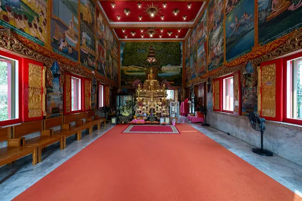 Tayland Nonthaburi 'deki Wat Chomphuwek' in içini süsleyen renkli duvar resimleri sunağı ve sakin bir atmosferde ahtan koltukları vurguluyor..