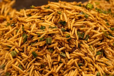 Canlı bir kızarmış şehriye gösterisi. Üstüne doğranmış yeşil otlar serpiştirilmiş. Akşamları kalabalık bir şehir pazarında sokak yemekleri kadar popüler..