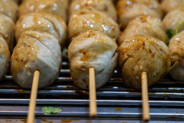 Dolgun bir gece marketinde ızgaranın üzerinde zengin bir jöleli köfte ile kaplanmış leziz şiş köfteler. Satıcılar lezzetli sokak yemekleri hazırlarken duman ve aromalar havayı dolduruyor..