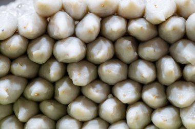 Geleneksel hamur köfteleri, gün ışığında yerel bir markette kendine özgü şekillerini ve dokularını sergileyerek düzgünce düzenlenir. Çevredeki tedarikçilerle atmosfer canlı ve canlı..