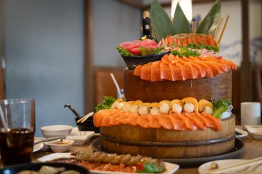 Masanın üzerinde çeşitli somon ve suşi çeşitlerinden oluşan güzel bir saşimi kulesi bulunuyor..