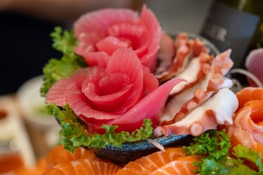 Somon ve ahtapot içeren güzel bir taze sashimi düzenleme, marul ile süslenmiş ve akşam boyunca bir suşi restoranında sanatsal bir şekilde sunuluyor..