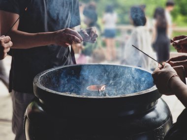 Tapınak töreninde tütsü çubuklarını yakın çekerken tütsü ocağından çıkan dumanla birlikte.