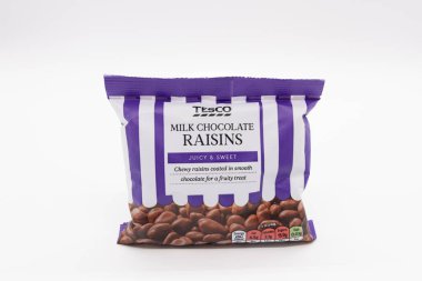 Irvine, İskoçya, İngiltere - 17 Haziran 2024: Tesco, grafik simgeleri ve ürün ile ilgili genel bilgileri gösteren plastik bir torba içinde çikolata kuru üzümleri paketini damgaladı.