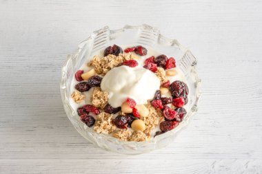 Bir kase dolusu çam fıstıklı yoğurt kurutulmuş yaban mersini ve kuru üzüm ideal, modern kahvaltı..