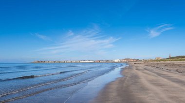 İskoçya 'daki Troon Körfezi' nin sularına bakıyorum. Mavi gökyüzü ve yumuşak sular sahili kaplıyor..