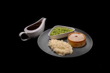 A Scotch or Kilmarnock steak mince pie served with mashed potatoes and mushy peas with a jug of gravy on the side. clipart