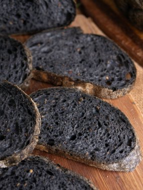 Tahtada dilimlenmiş taze pişmiş siyah kömür hamurlu ciabatta ekmeği.