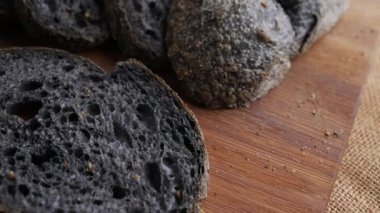 Tahtada dilimlenmiş taze pişmiş siyah kömür hamurlu ciabatta ekmeği..