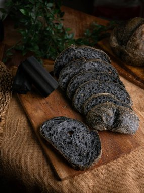 Tahtada dilimlenmiş taze pişmiş siyah kömür hamurlu ciabatta ekmeği.