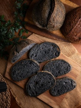 Tahtada dilimlenmiş taze pişmiş siyah kömür hamurlu ciabatta ekmeği.