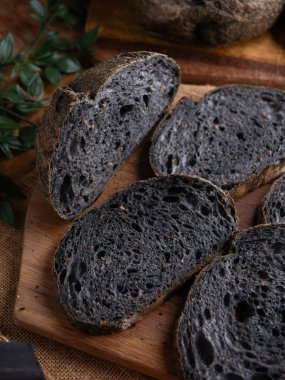 Tahtada dilimlenmiş taze pişmiş siyah kömür hamurlu ciabatta ekmeği.