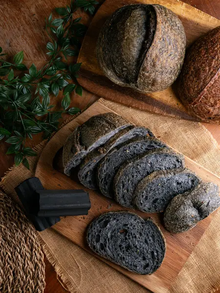 Tahtada dilimlenmiş taze pişmiş siyah kömür hamurlu ciabatta ekmeği.