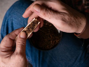 Kurutulmuş tütünle sarılmış sigara hazırlıyorum..