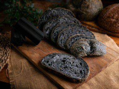 Tahtada dilimlenmiş taze pişmiş siyah kömür hamurlu ciabatta ekmeği.