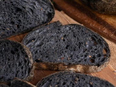 Tahtada dilimlenmiş taze pişmiş siyah kömür hamurlu ciabatta ekmeği.