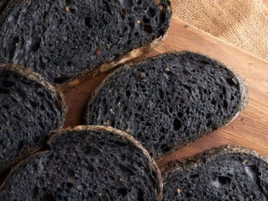 Tahtada dilimlenmiş taze pişmiş siyah kömür hamurlu ciabatta ekmeği.