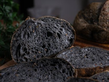 Tahtada dilimlenmiş taze pişmiş siyah kömür hamurlu ciabatta ekmeği.