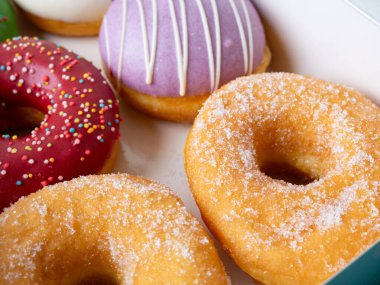 Farklı renkte krema dizaynlı çörekler bir kutuda dizilmiş..