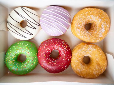 Farklı renkte krema dizaynlı çörekler bir kutuda dizilmiş..