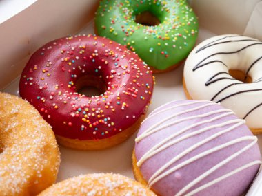 Farklı renkte krema dizaynlı çörekler bir kutuda dizilmiş..