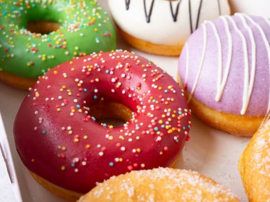 Farklı renkte krema dizaynlı çörekler bir kutuda dizilmiş..