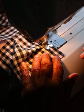 Dikiş makinesiyle çalışan kıdemli kadın. Yaşlı Eller Yetenekli İş gücü vasıtasıyla Giysi Oluşturuyor