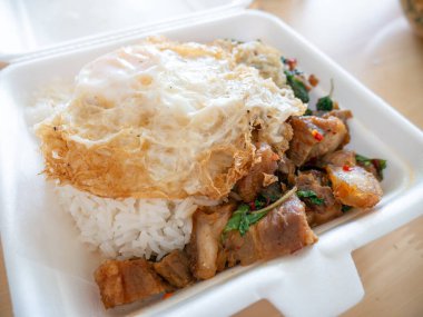 Kızarmış yumurtalı kızarmış domuz fesleğeni ve köpük kutusu..