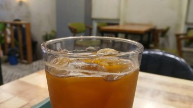 Tahta bir masada, Plastik Bardakta buzlu kahve.