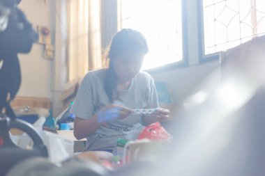 Odasını temizleyen ve gereksiz şeyleri temizleyen bir kadın. Doğal işaret fişeği de dahil.