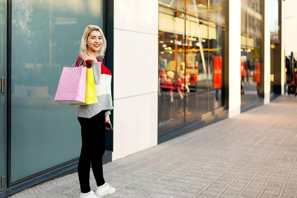 站在购物中心旁边拿着购物袋的金发女人 — 图库照片