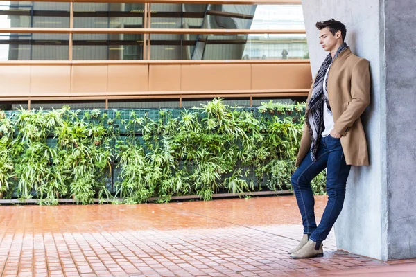 Stock image Young man wearing winter clothes in the street. Young guy with modern hairstyle with coat, blue jeans and white sweeter.