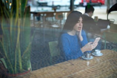 Genç kadın kullanım cep telefonu iş tatilinde, mutlu erkek moda haberleri cep telefonu restoranda kahvaltı sırasında okuma büyüleyici rahat kafede otururken portresi