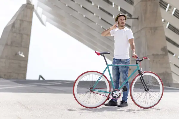 Bisikletiyle Işe Giderken Cep Telefonunu Kullanan Genç Bir Adamın Fotoğrafı Stok Fotoğraf