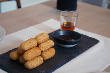 Churros, gri arka planda pudra şekeri serpiştirilmiş.